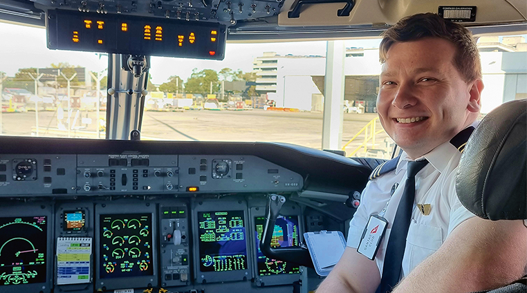 A pilot in the cockpit, smiling at camera