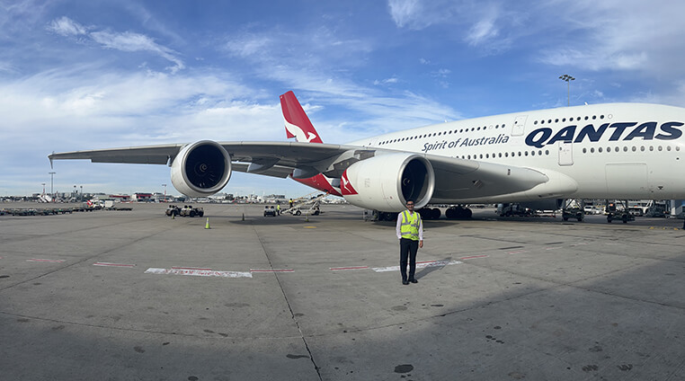 A Qantas Graduate on the tarmac in front of a plane